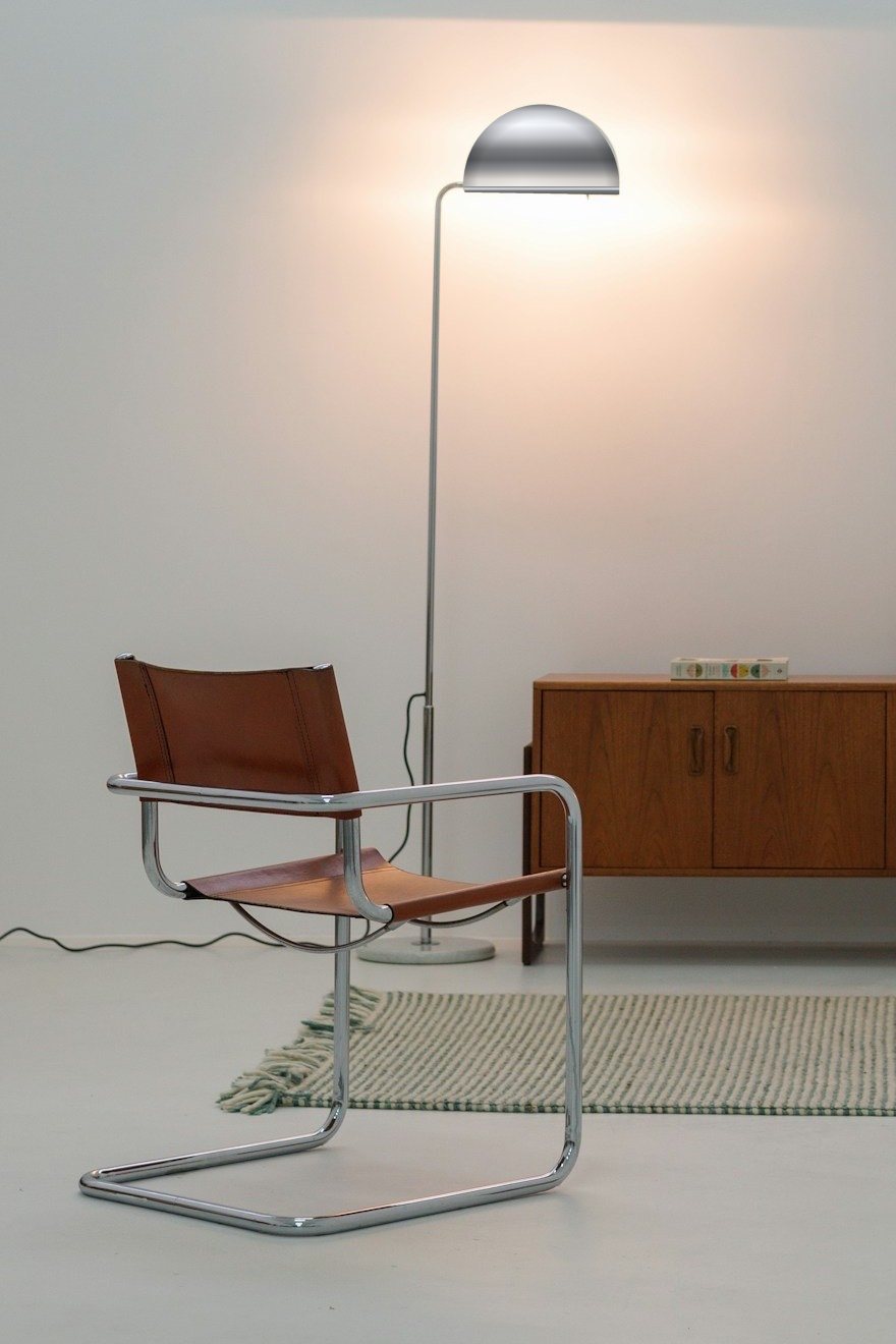 Verchroomde sledestoel met leer naast een staande lamp
